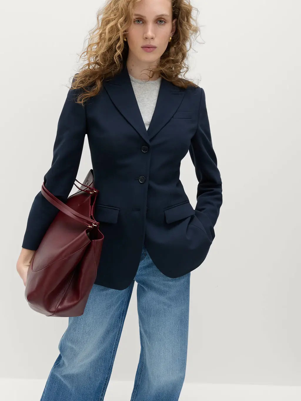 Woman wearing a grey top with a navy blazer and blue jeans