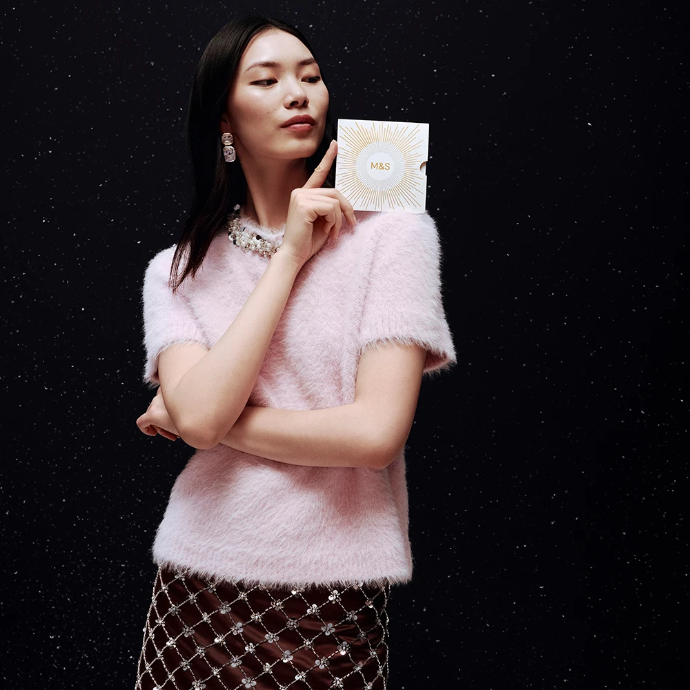 Assorted M&S gift cards in the snow surrounded by a red ribbon
