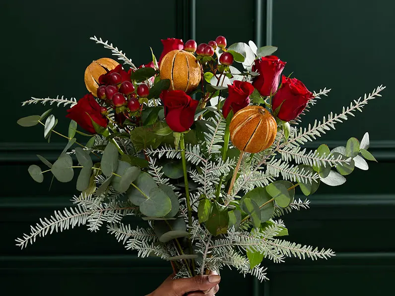 Bouquet of season flowers with eucalyptus, red roses and dried oranges.