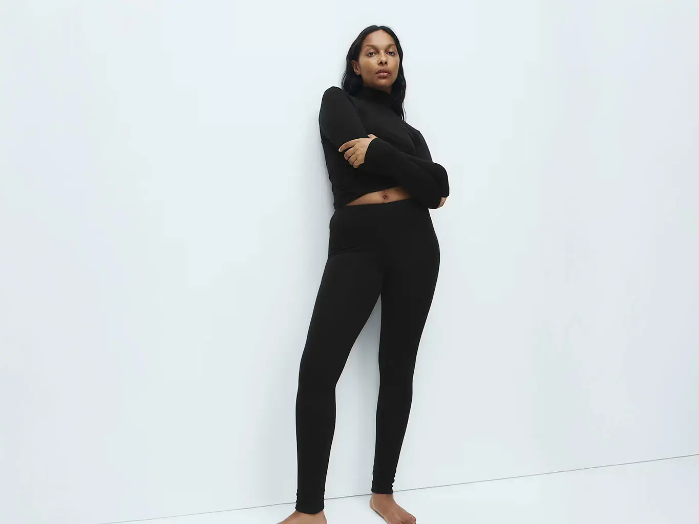 Woman wearing a black thermal mock-neck top with black thermal leggings