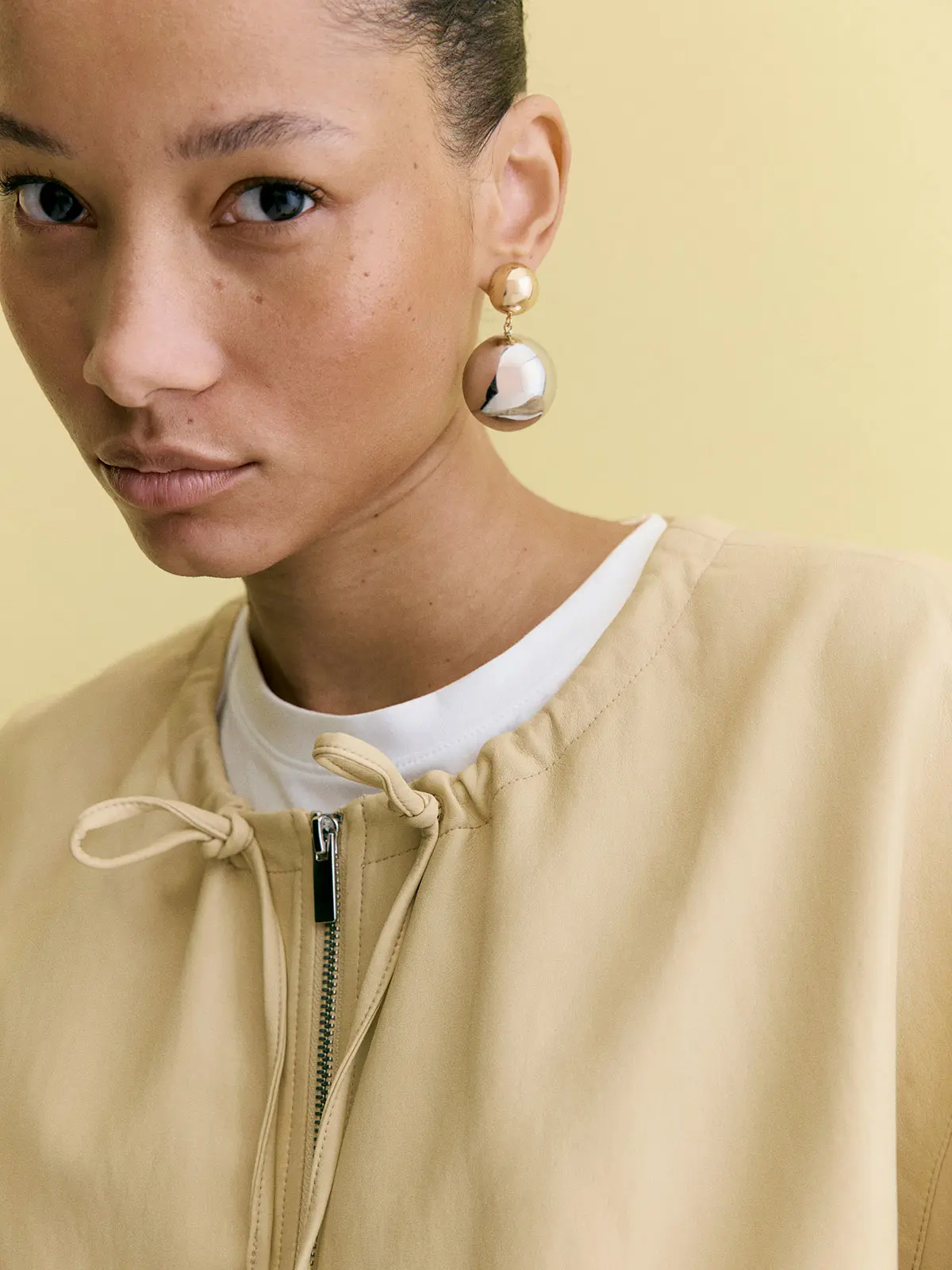Woman wearing yellow jacket over white T-shirt with statement earrings 