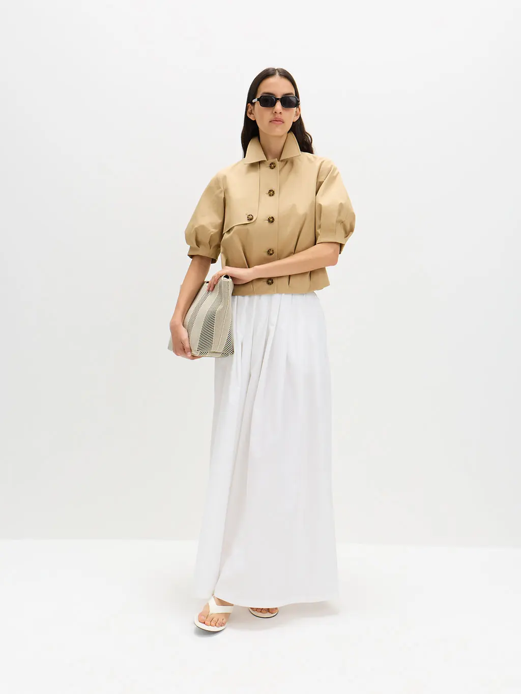 Woman wearing a white skirt and camel jacket 