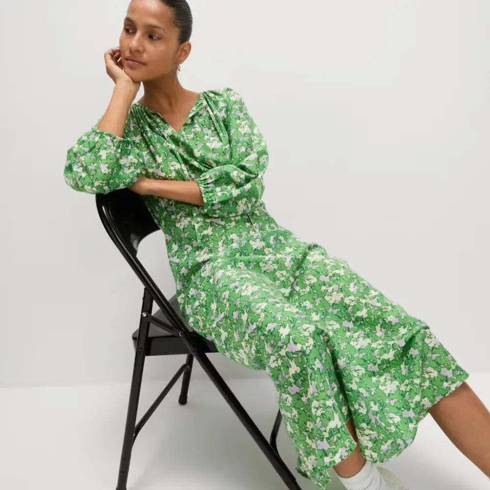A woman sat on a chair wearing a green floral midi dress