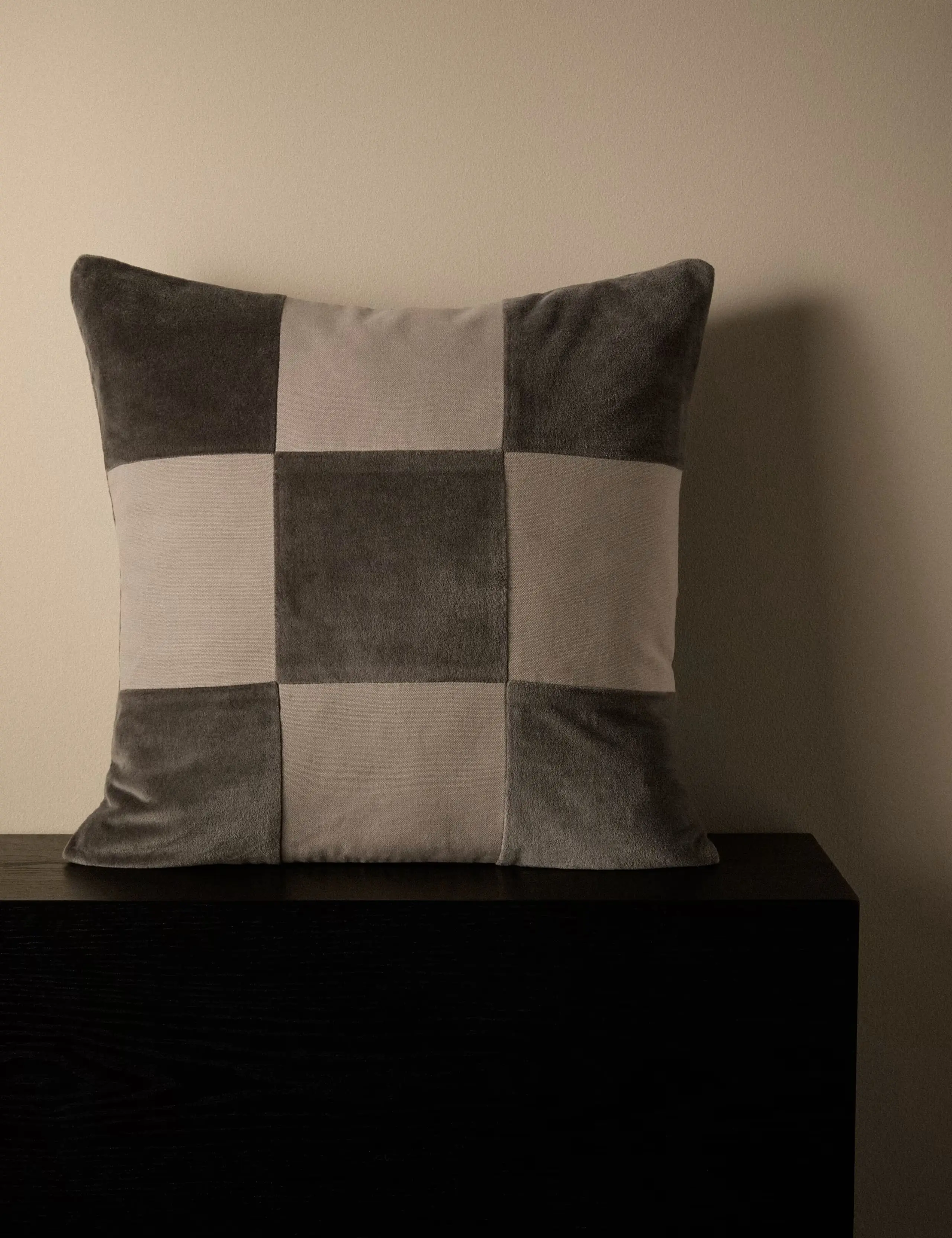 Taupe chequerboard square cushion made from a soft velvet-like fabric.