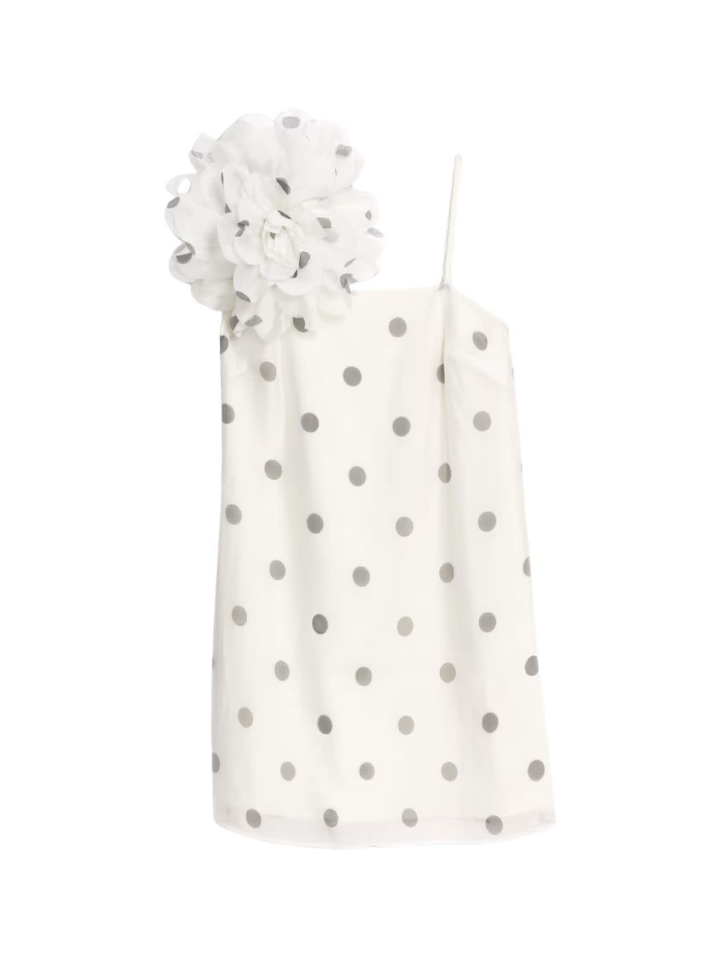 A short mini dress covered in polka dots and with a large corsage on the shoulder