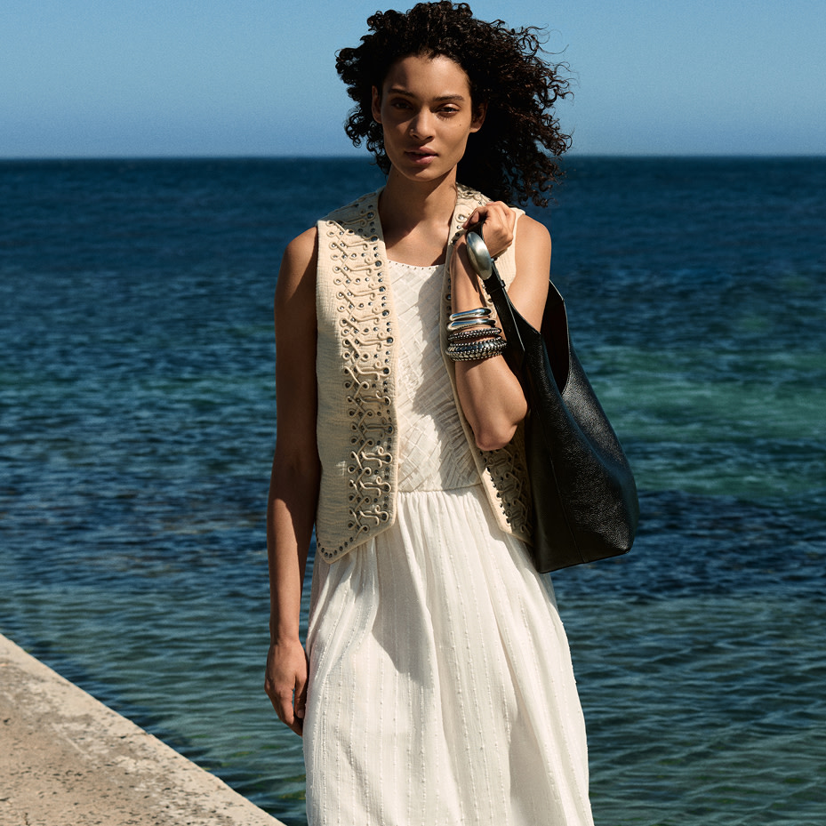 Woman in white dress and waistcoat on beach