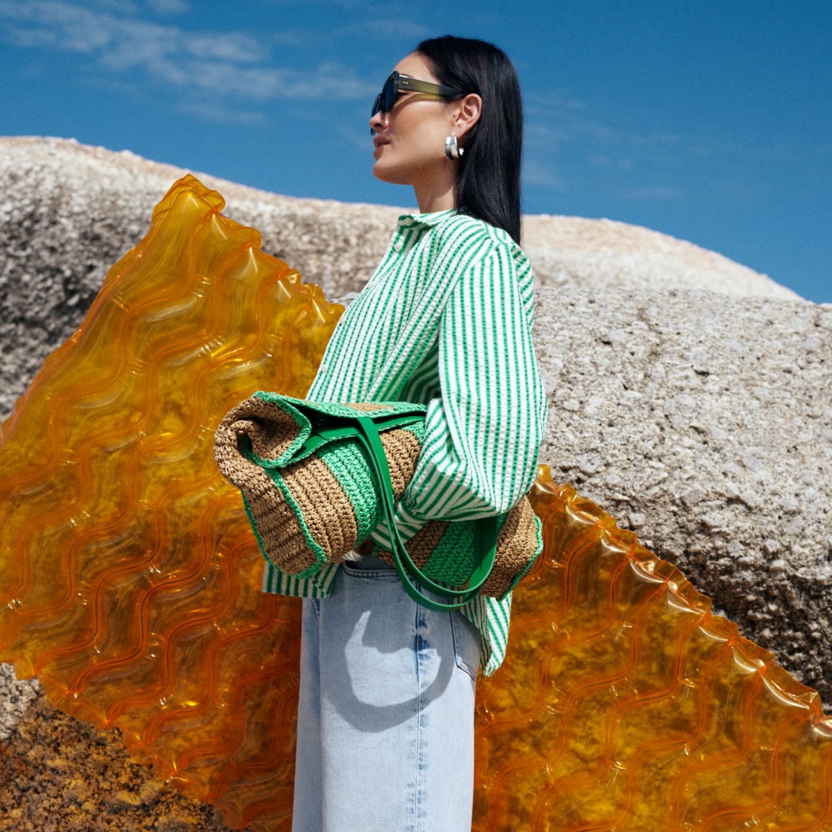 Woman wearing green shirt holding straw bag