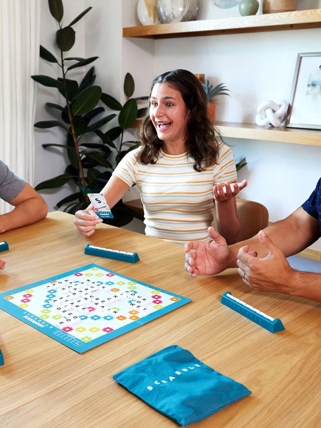 Teenager playing Scrabble board game with family