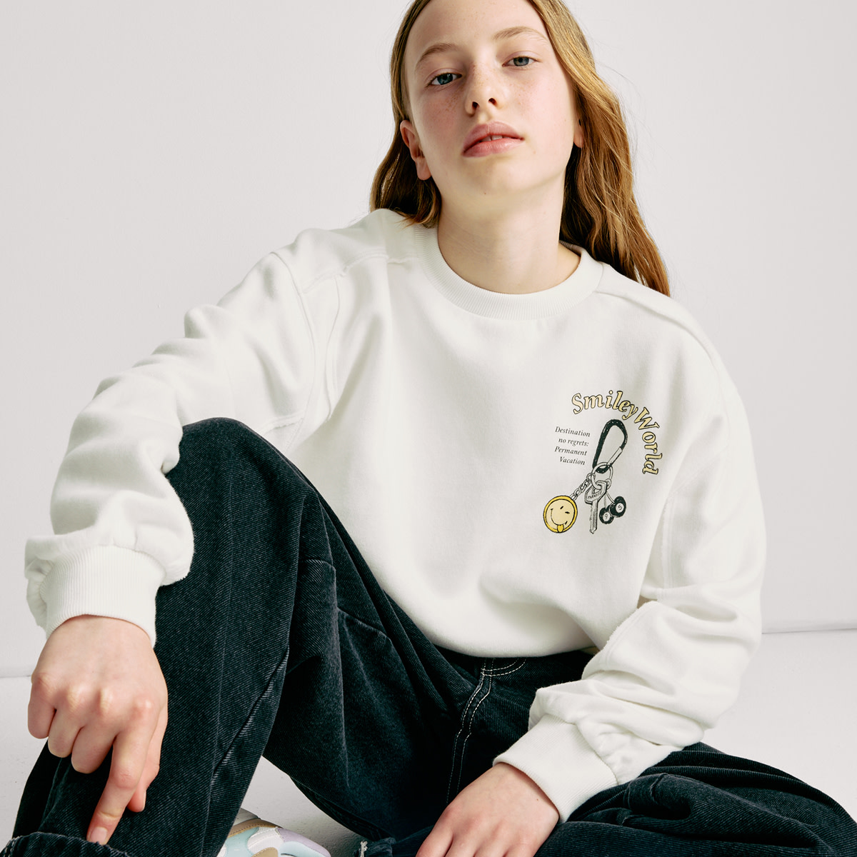 Girl wearing cream sweatshirt with logo on. Shop now