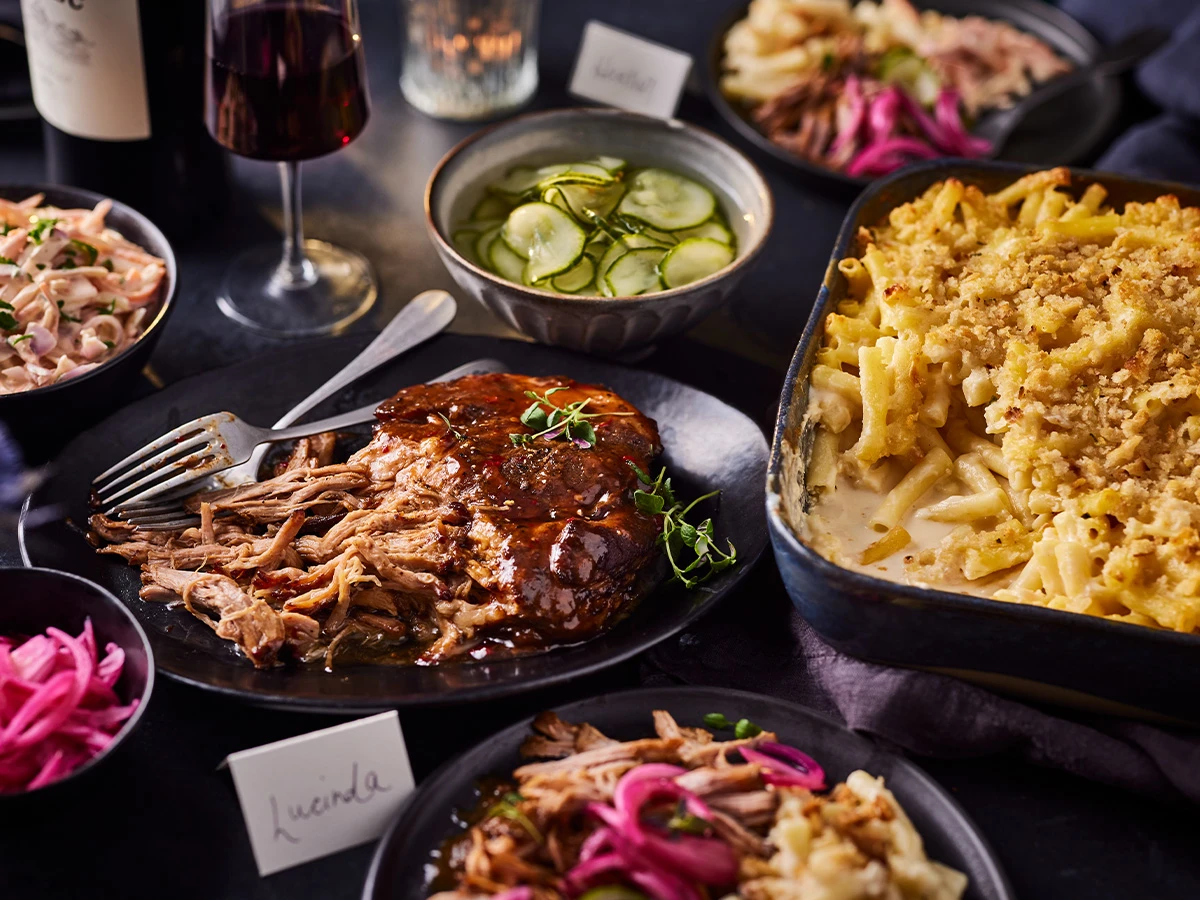 A slow cooked pork belly with macaroni cheese and glasses of red wine 