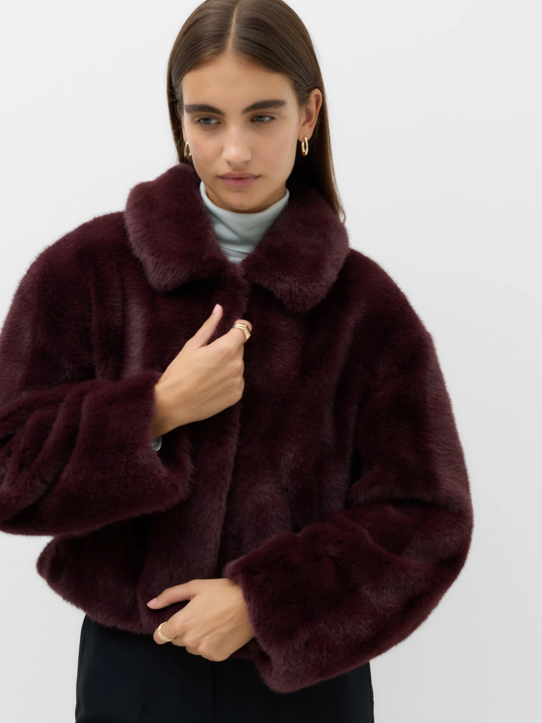 Model wearing a burgundy faux fur short jacket with a collar.
