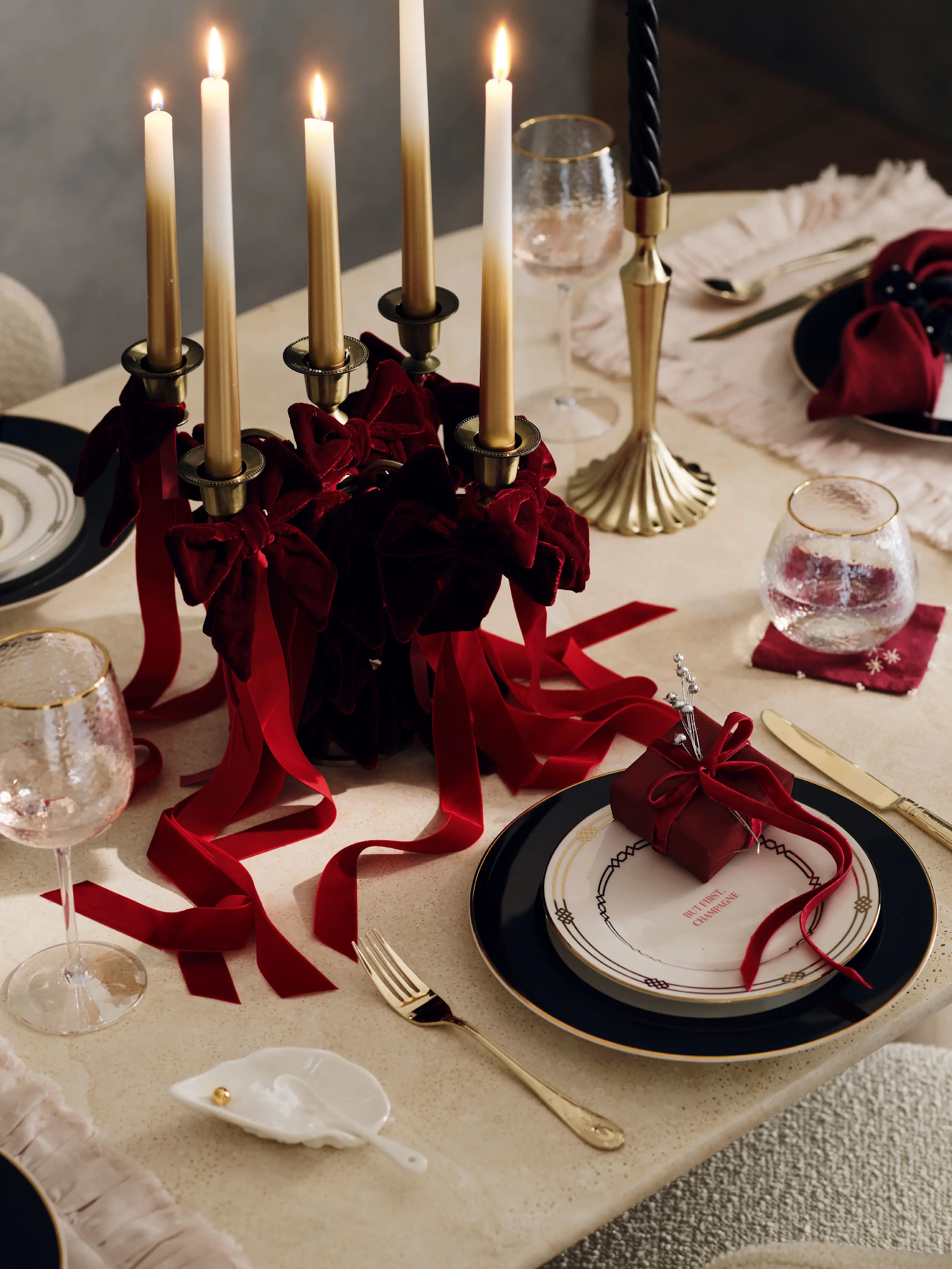 Image of festive table decor including plates, cutlery, candles and red ribbons