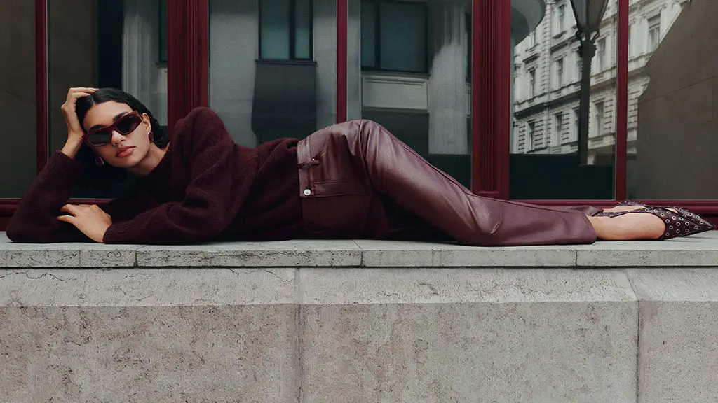 Woman wearing burgundy knitted jumper and faux leather trousers