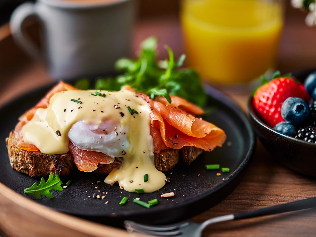 A plate of breakfast in bed with smoked salmon, hollandaise and poached eggs