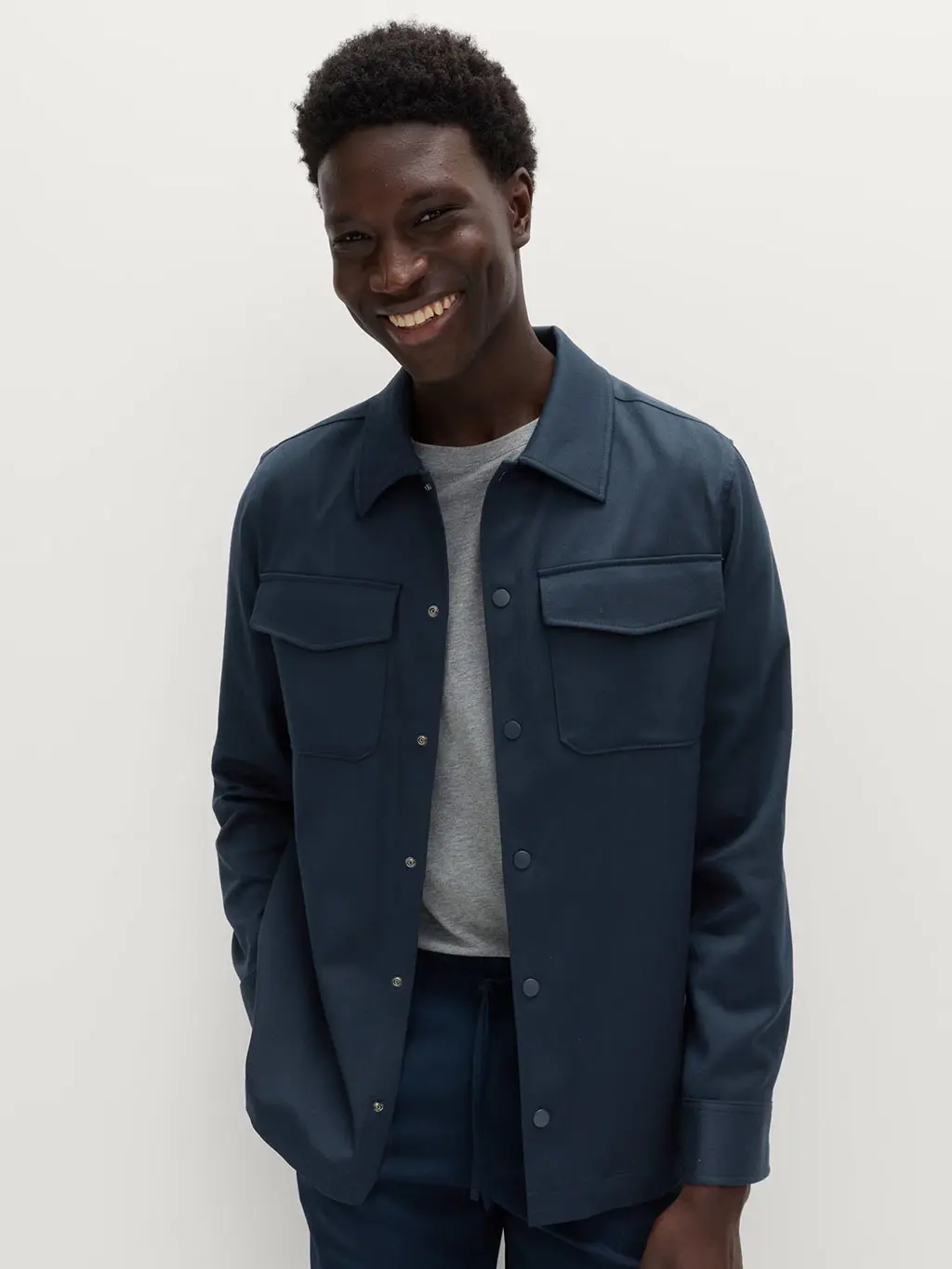 Man wearing a grey T-shirt with a navy shacket and smart trousers