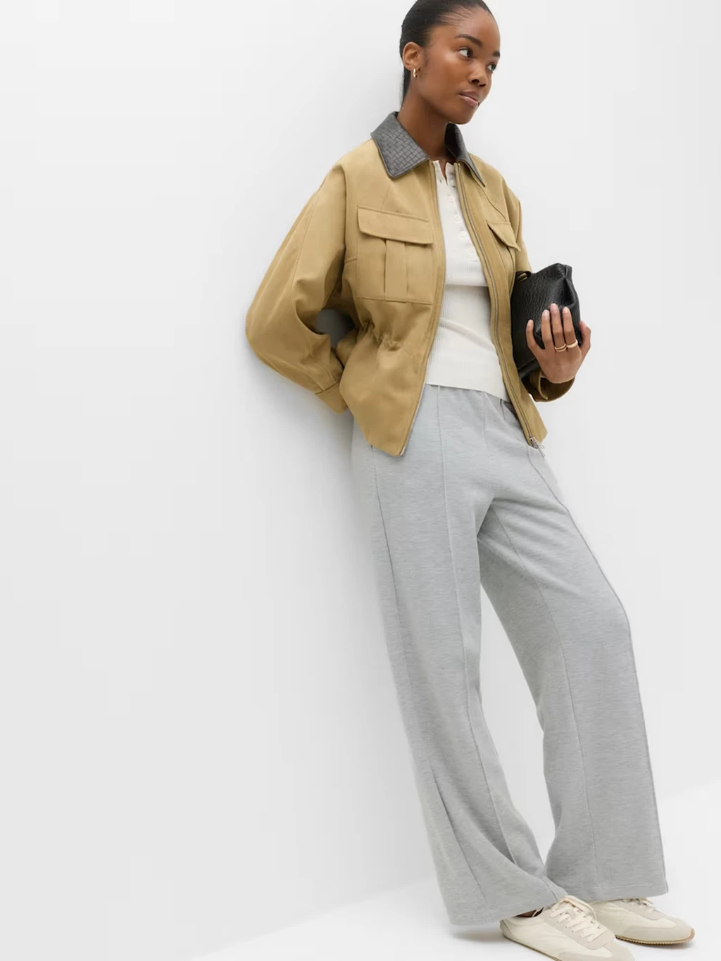 Woman wearing a pair of grey wide-leg joggers with a white T-shirt and beige coat.