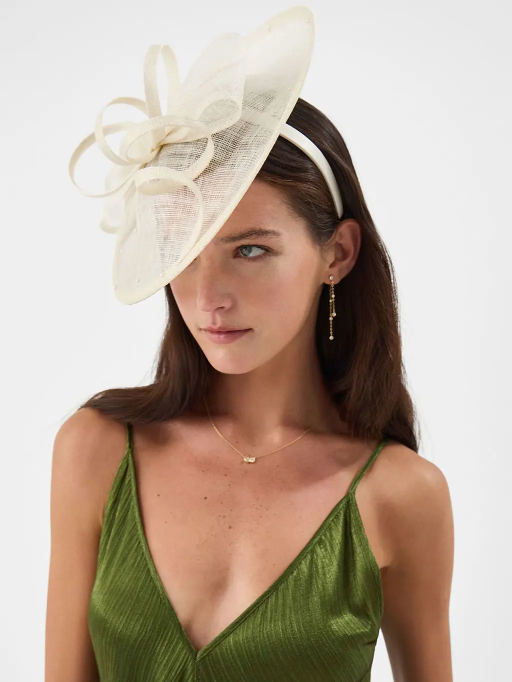 Woman wearing green dress and white fasinator