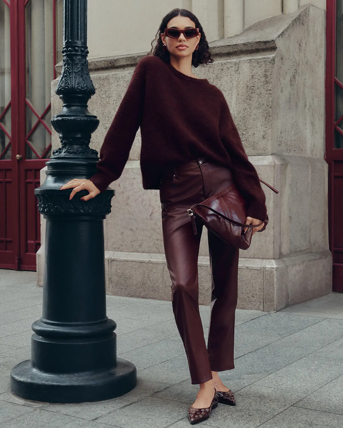 Woman wearing burgundy knitted jumper and faux leather burgundy trousers