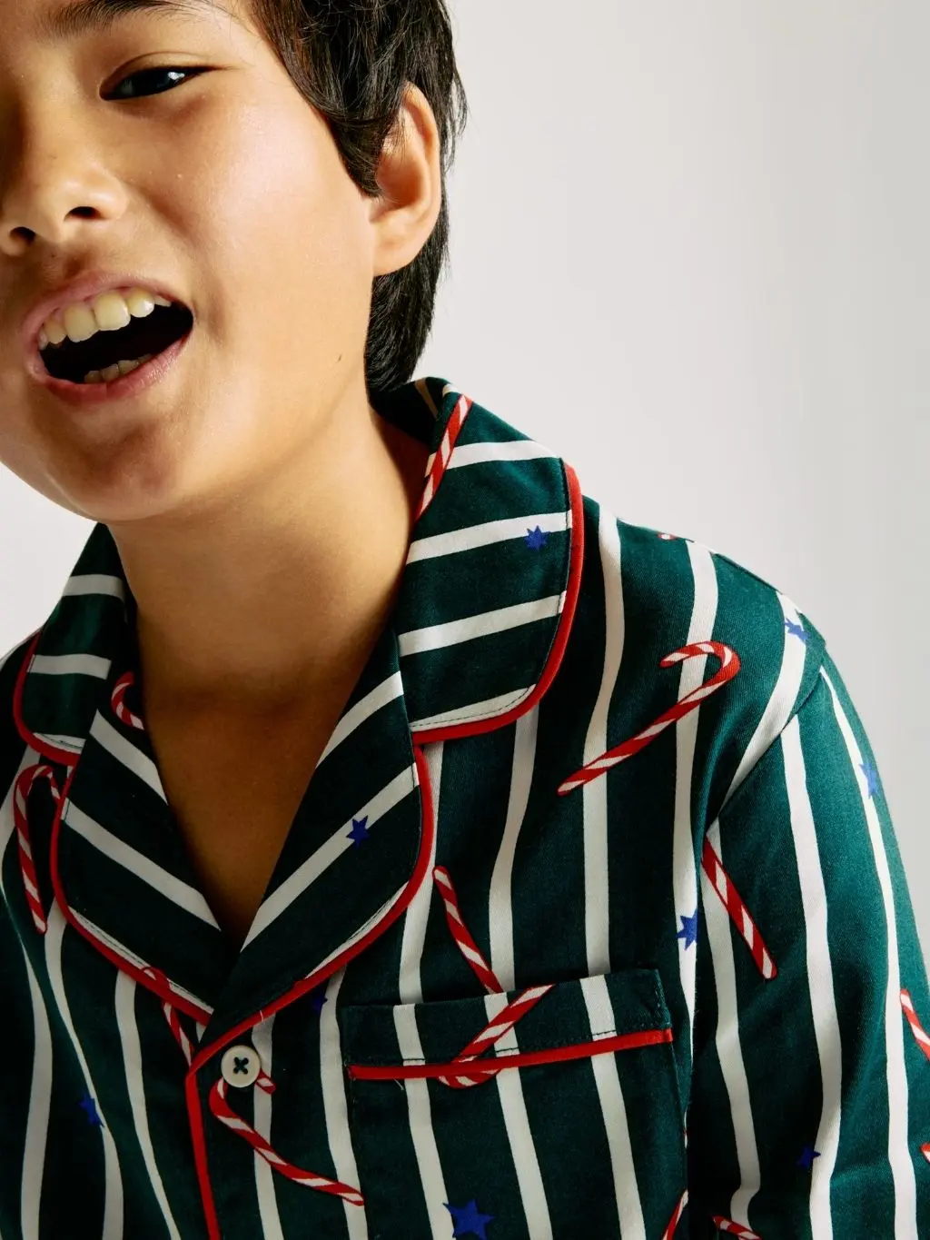 A young boy wears Candy Cane Christmas pyjamas by M&S