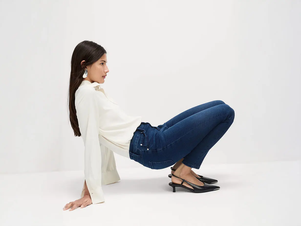 Woman in white blouse, blue skinny jeans and black kitten heels 