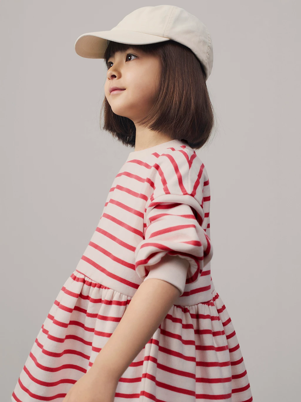 Girl wearing cream cap and red striped dress
