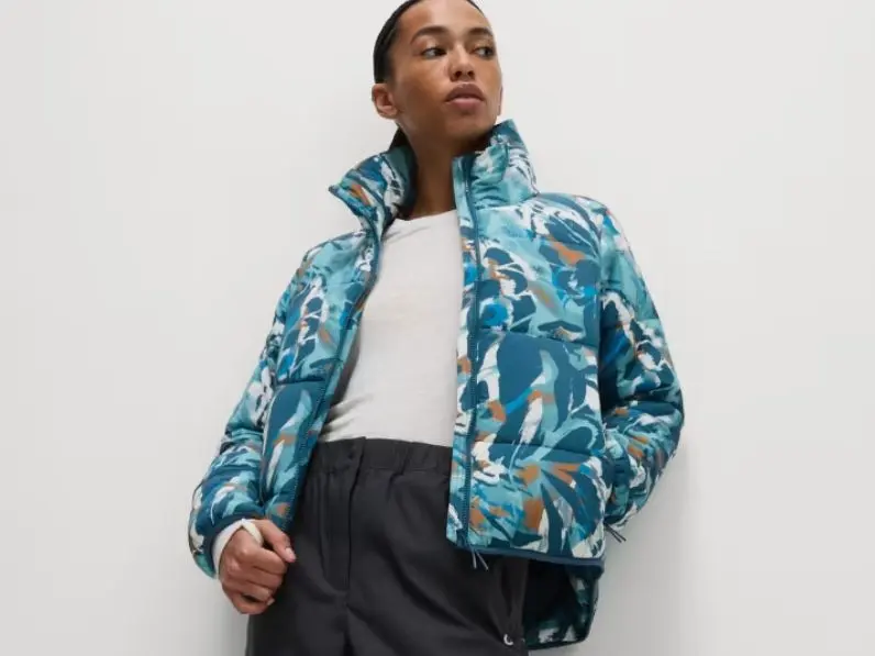 A woman wears a Good Move patterned puffa jacket and white t-shirt