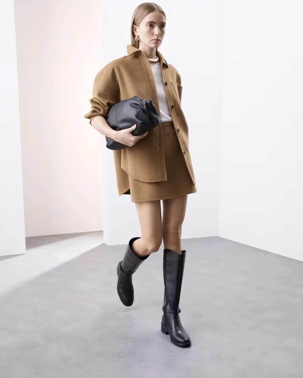 Woman wearing a beige shirt, mini skirt and knee-high boots