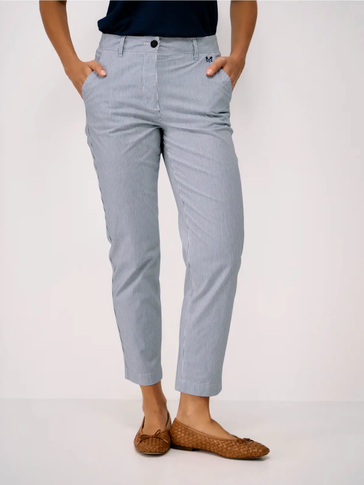 Woman wearing blue striped tapered trousers and brown woven flats