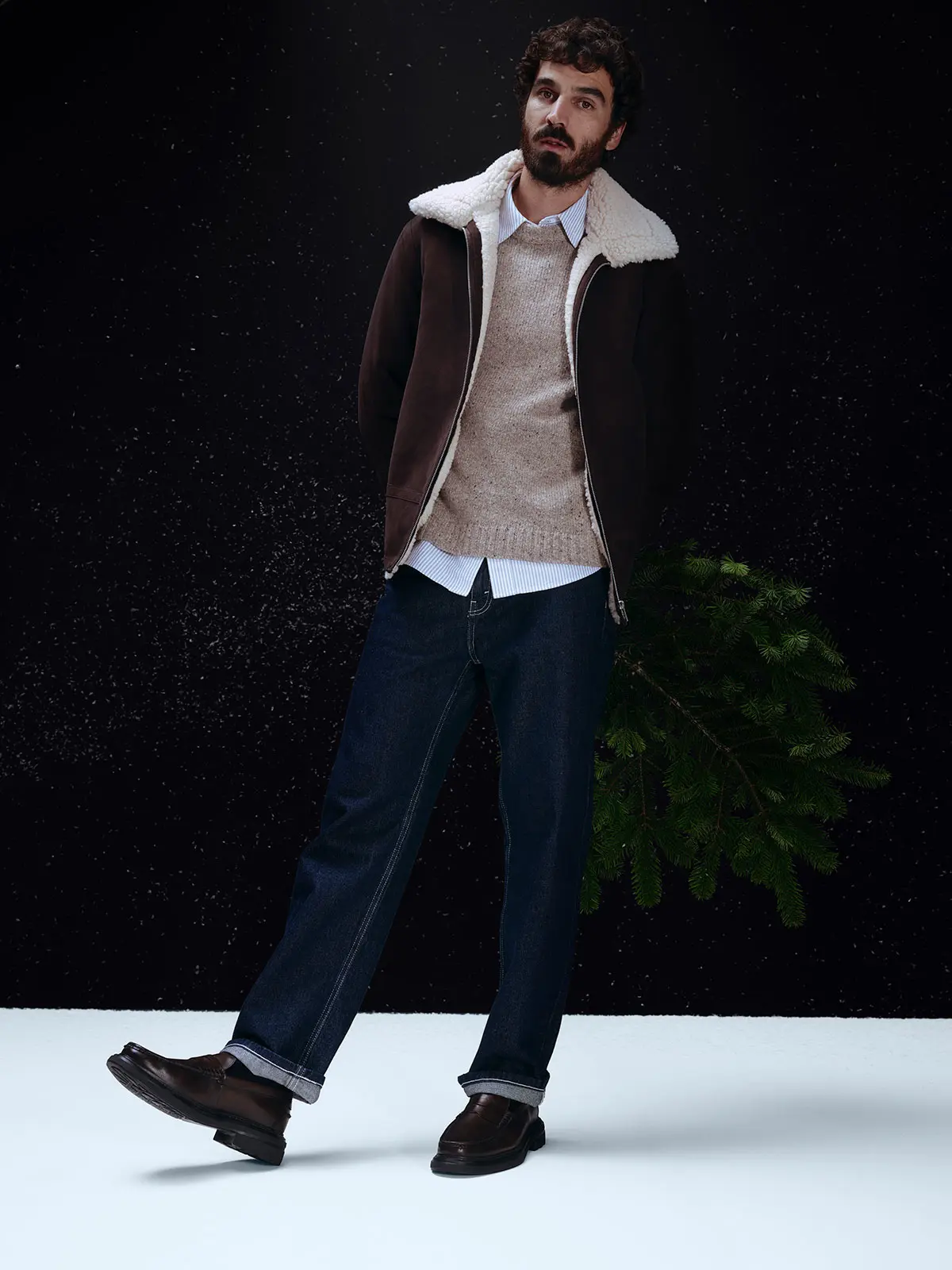 Man wearing blue striped shirt, oatmeal jumper, borg-lined jacket, blue jeans and smart shoes