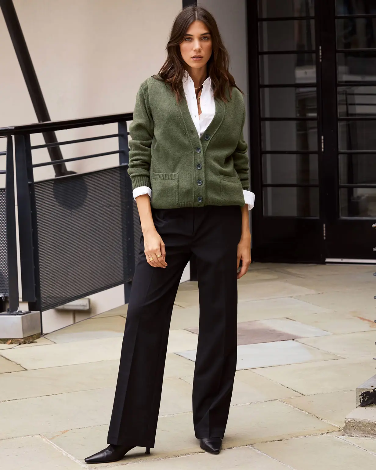 Woman wearing white shirt under green cardigan, black trousers and heeled boots