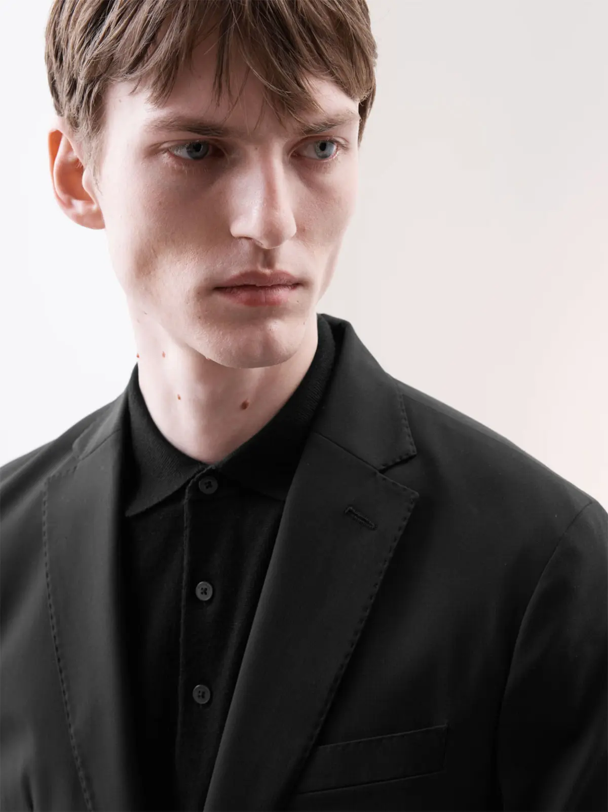 Man wearing black blazer over black polo top 