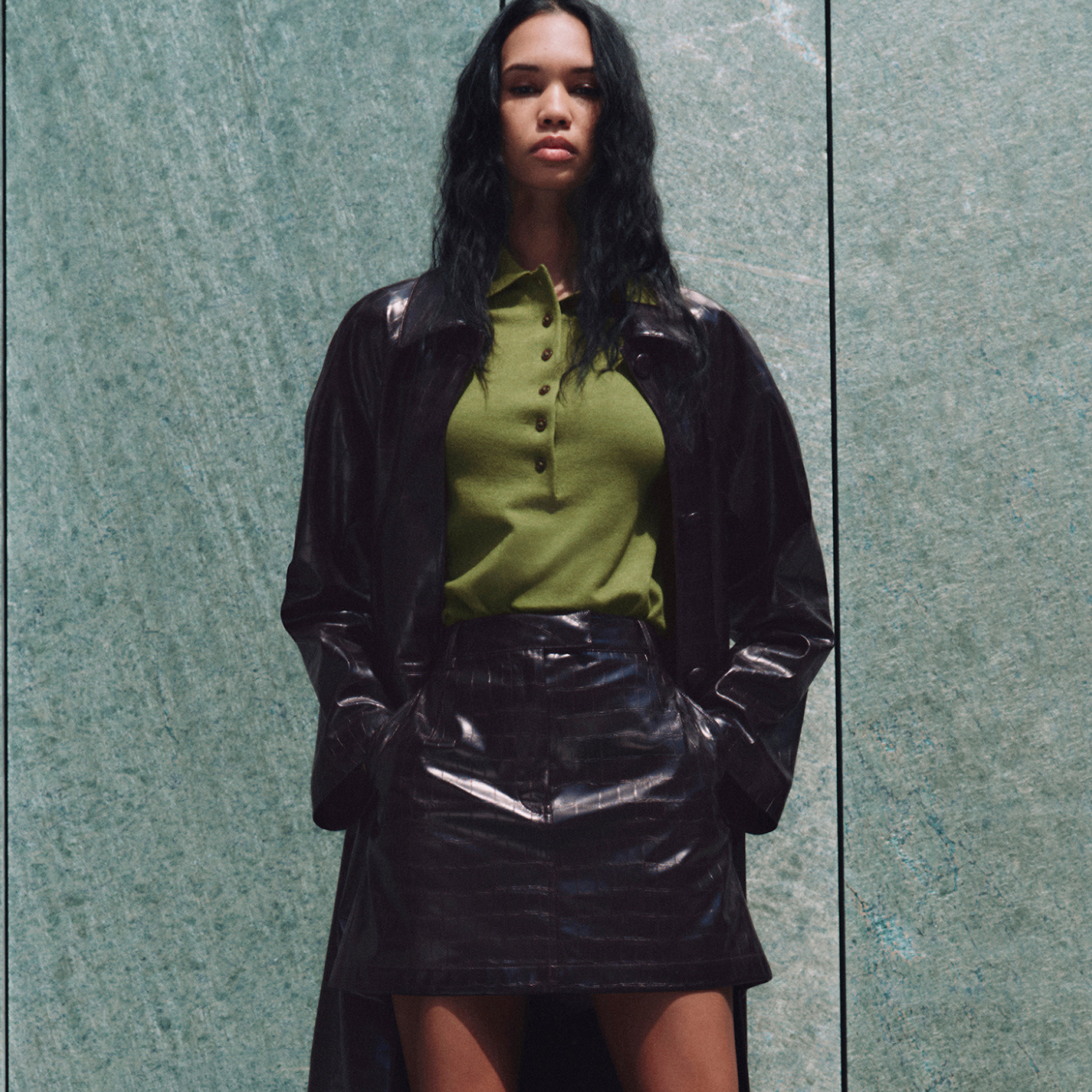 Woman wearing leather coat and matching mini skirt over green top