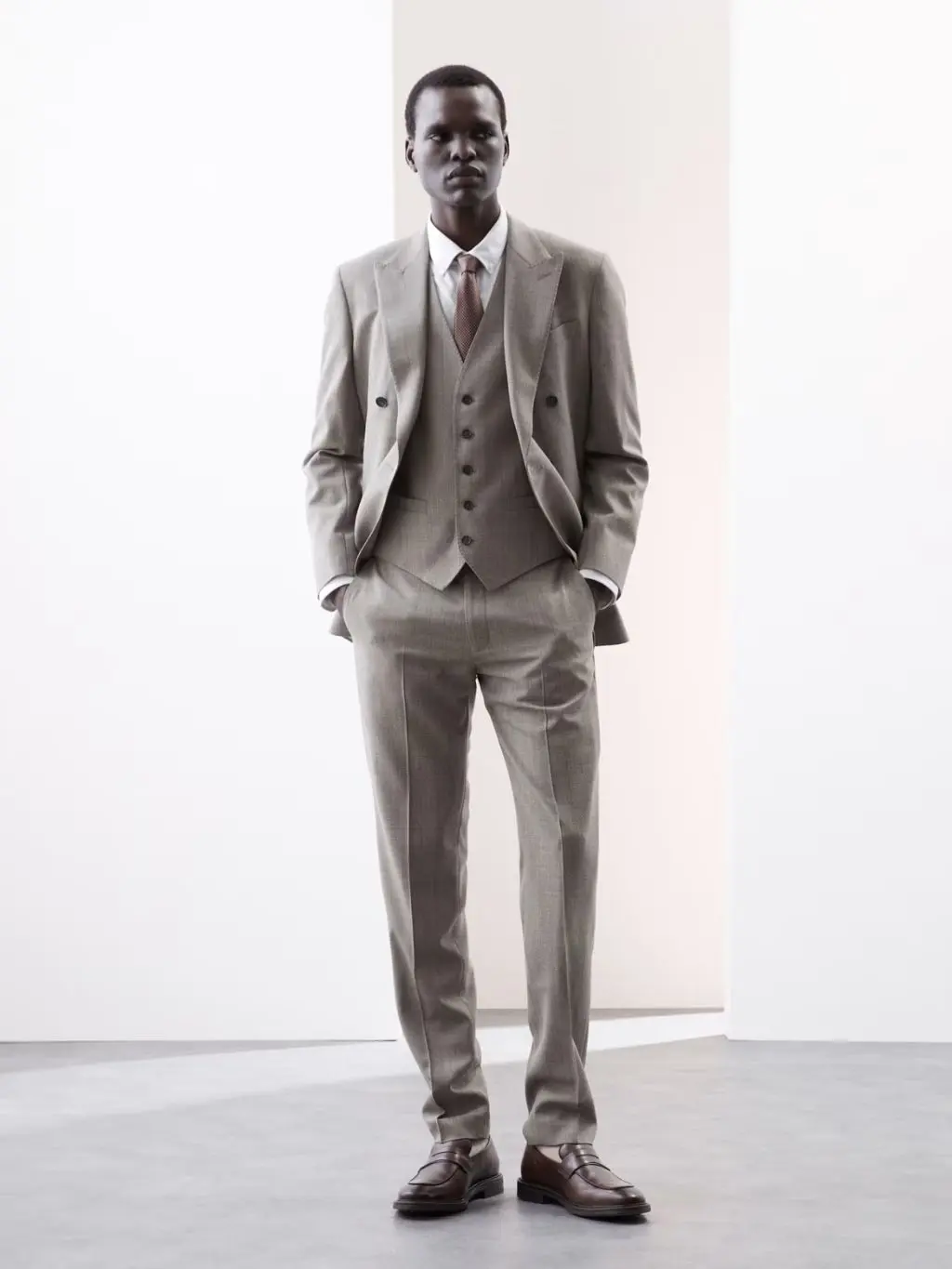 A man wearing a three-piece grey suit, shirt and tie suit shot in a studio