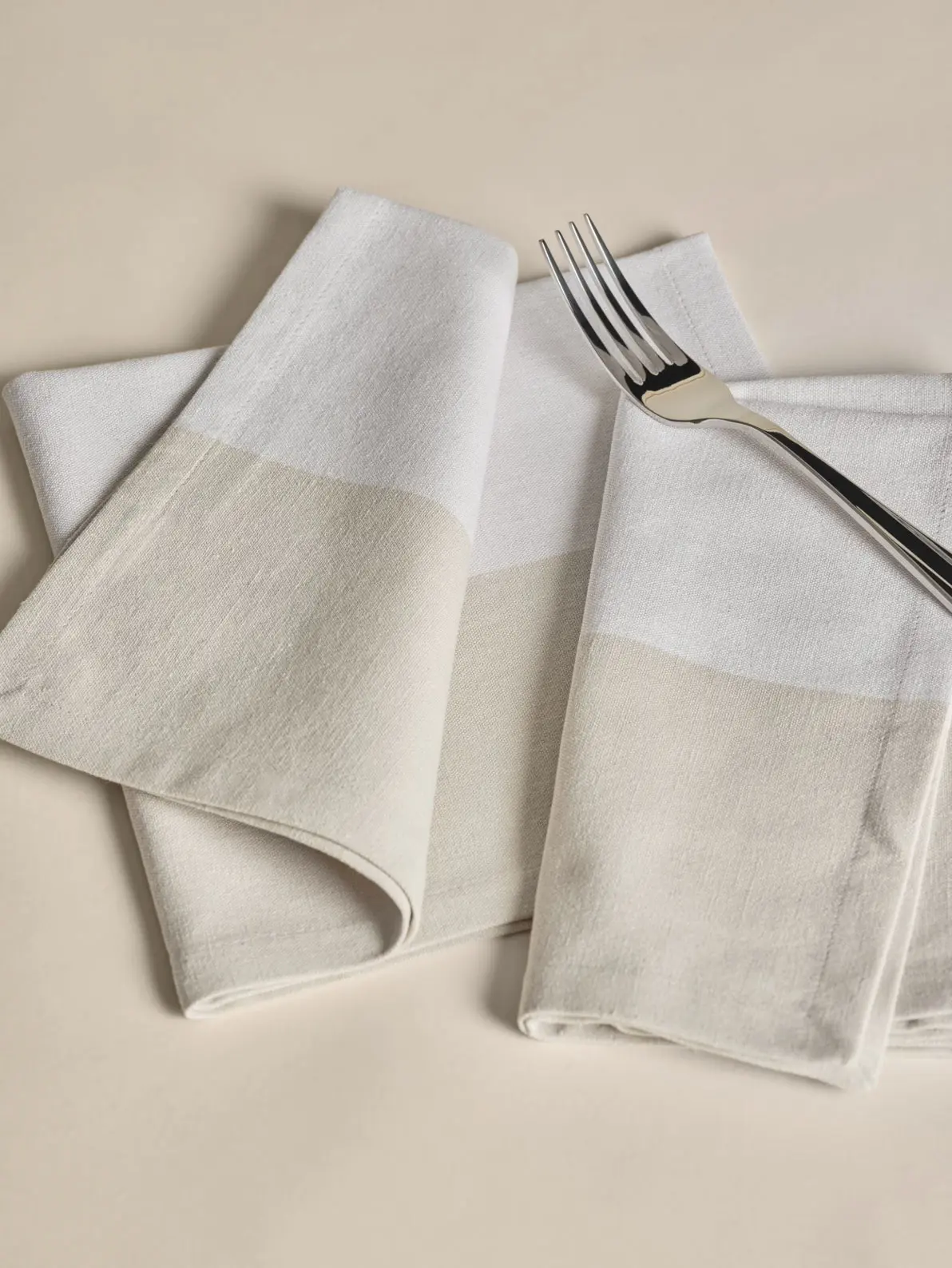Beige and white napkins and a silver fork