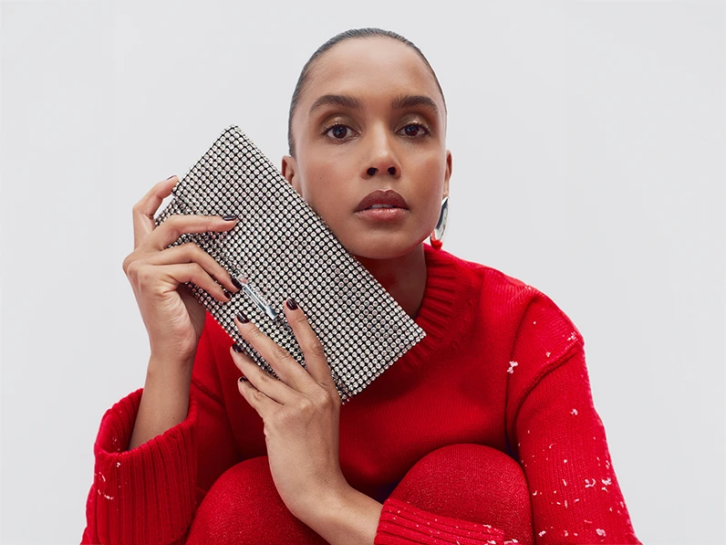 Woman wearing red jumper holding a diamanté clutch bag