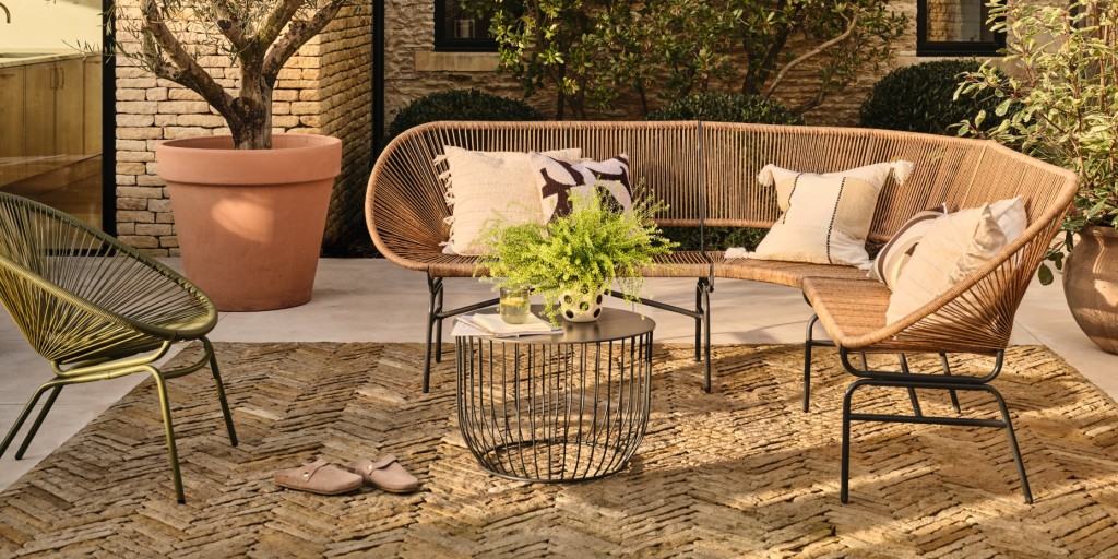 An L-shaped garden sofa with cream cushions, a table and a chair. Shop garden furniture

