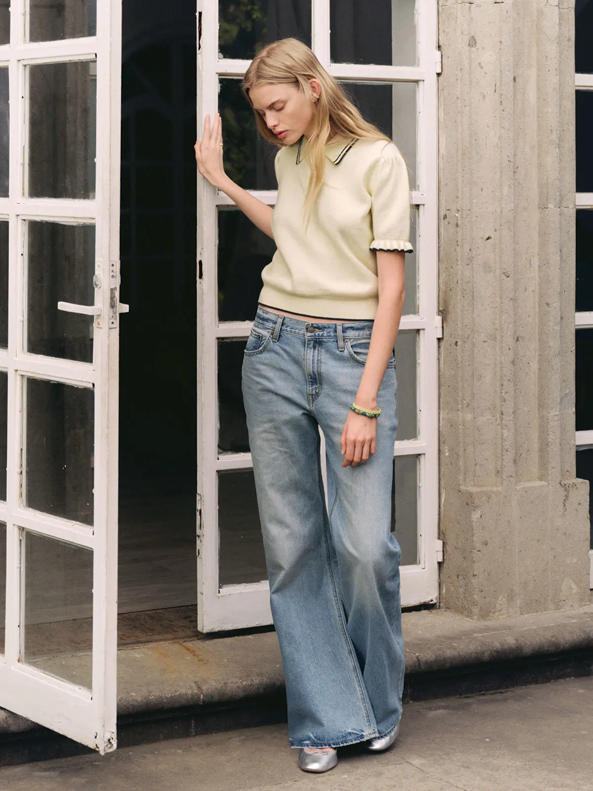 Woman wearing blue Levi's jeans, a neutral top and metallic flats 