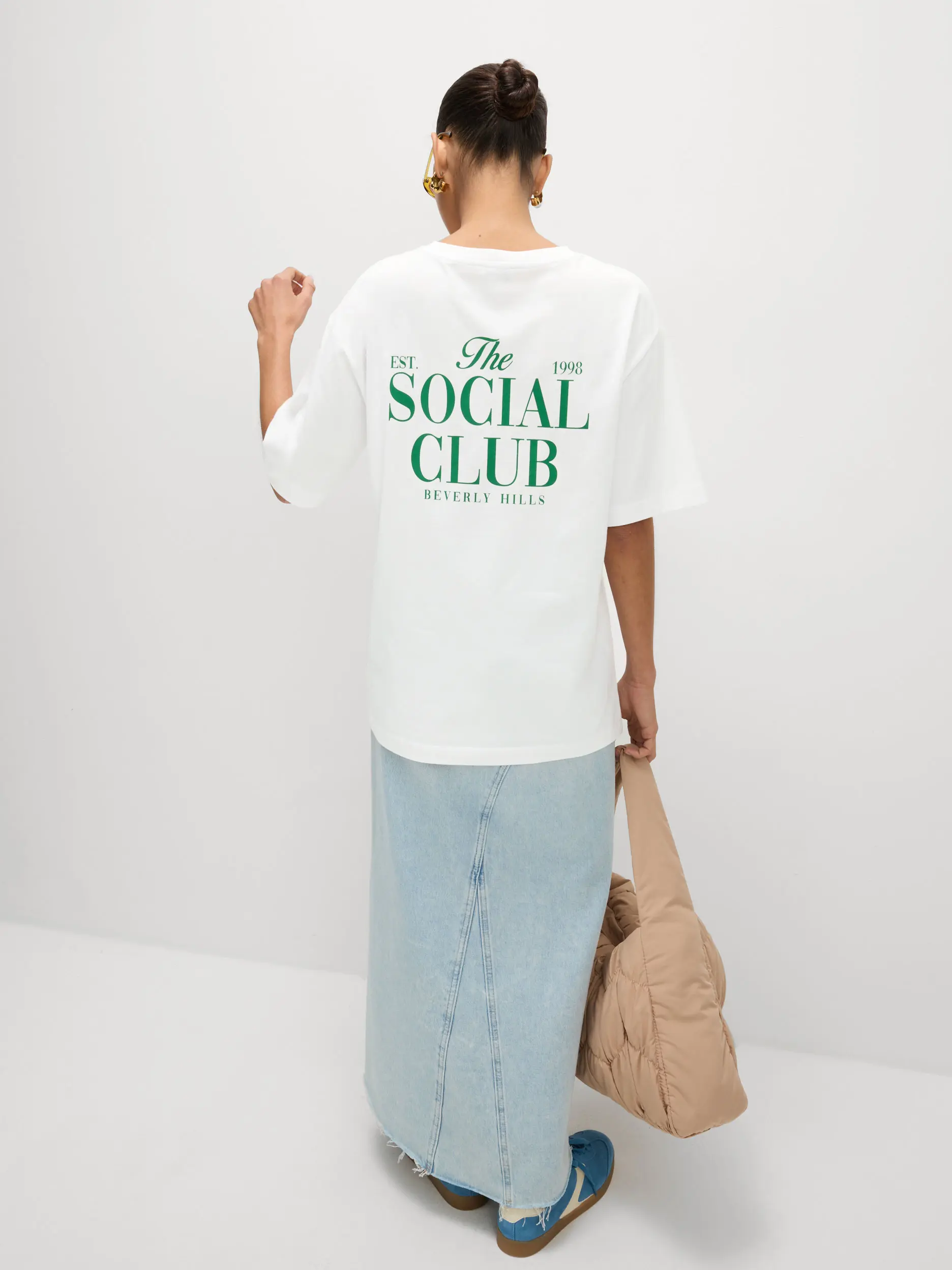 Woman wearing an oversized graphic white T-shirt and denim midi skirt