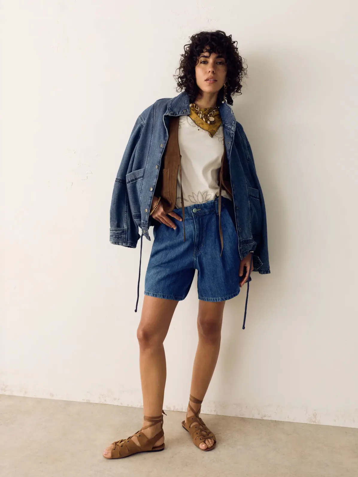 Woman wearing denim shorts, denim jacket and brown sandals 