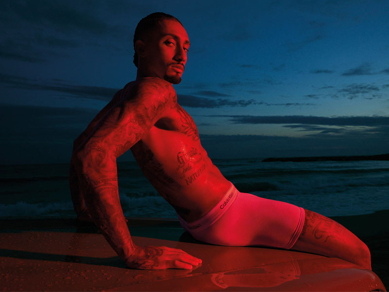 man sitting on beach in white boxers 