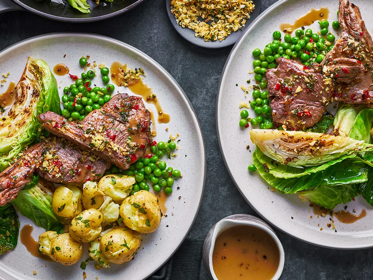 A plate of lamb cutlets with potatoes and peas