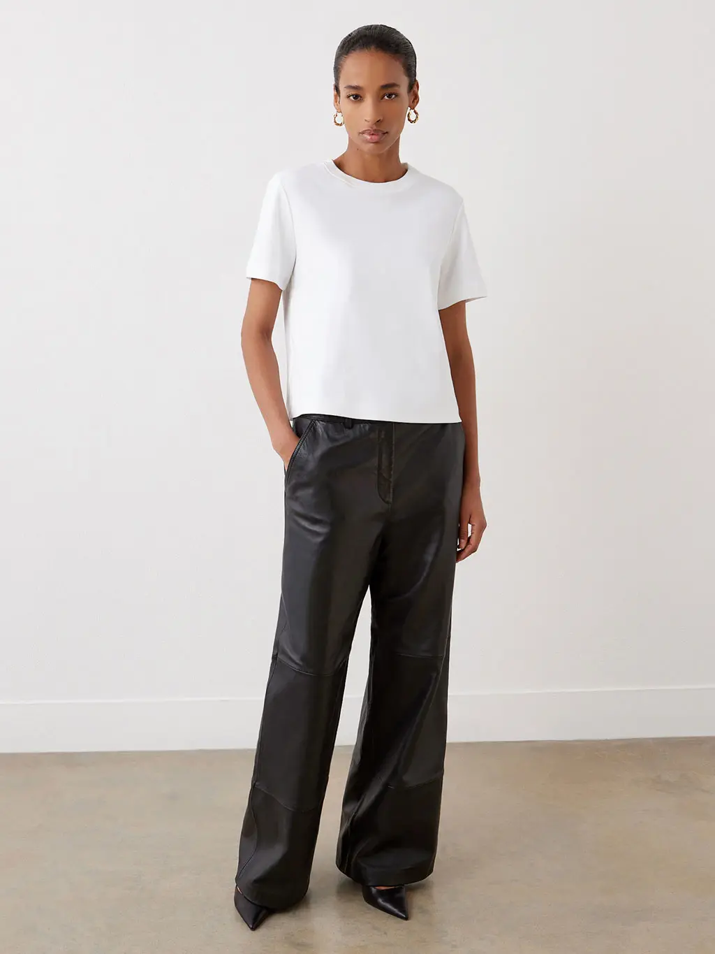 Woman wearing a white T-shirt and flared black leather trousers