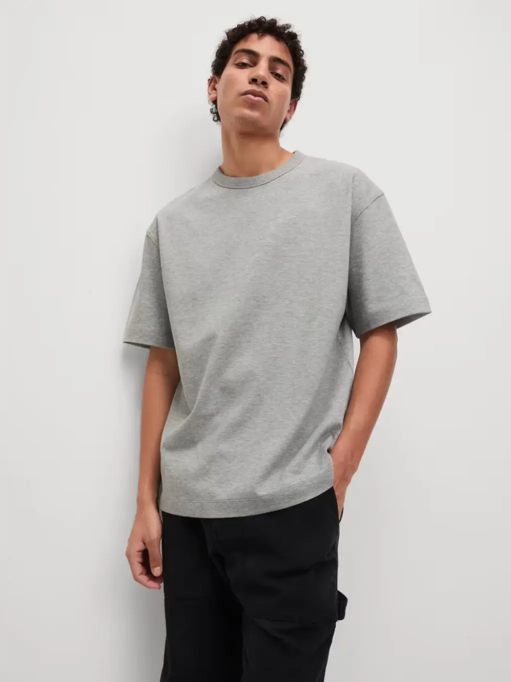 A man wears a grey oversized t-shirt