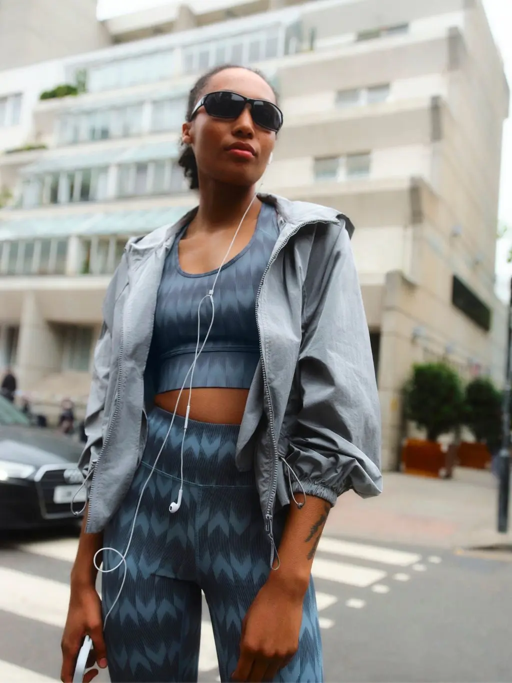 A woman wears a matching sports bra for smaller breasts and matching leggings with a sports jacket over the top