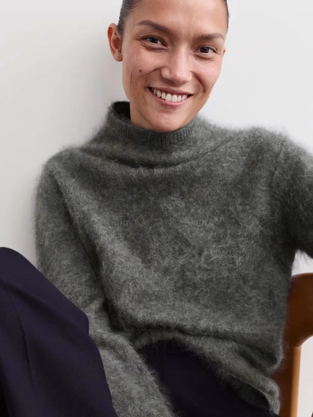 Woman wearing grey funnel-neck jumper with navy trousers