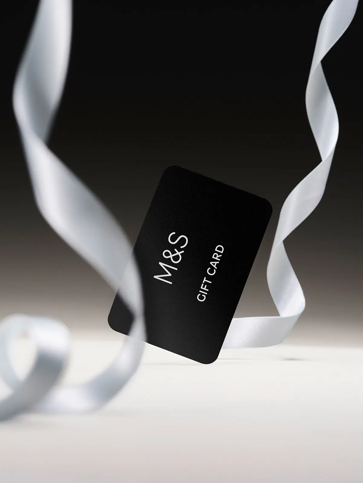 M&S gift card in black, plus white ribbon