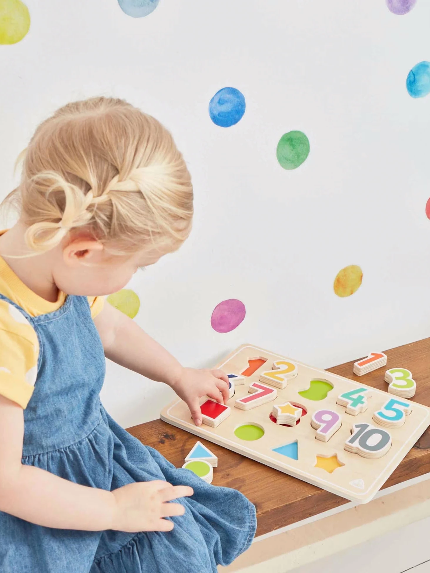 Girl playing with wooden numbers jigsaw by the Early Learning Centre