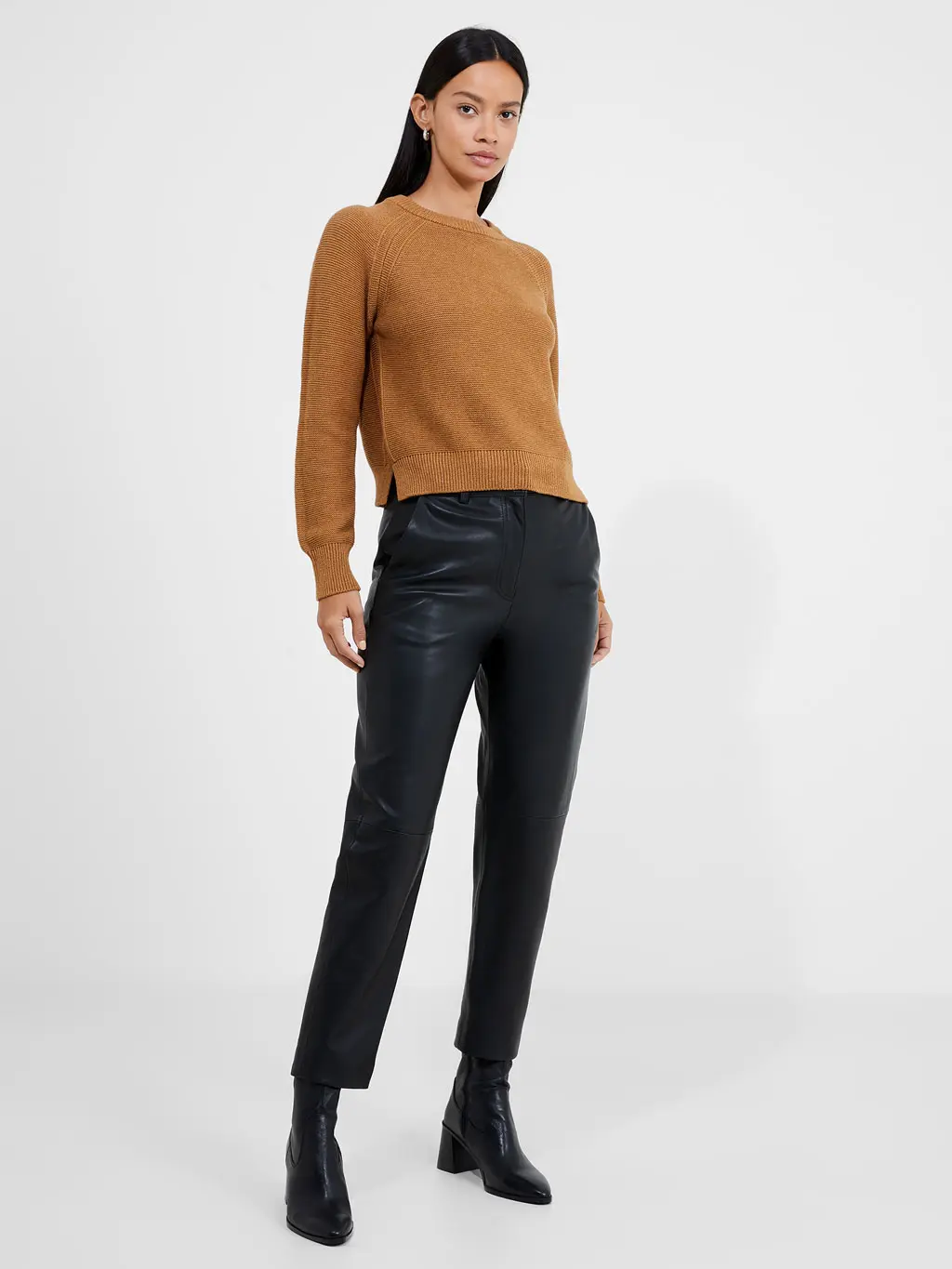Woman wearing black leather trousers, black boots and an ochre jumper