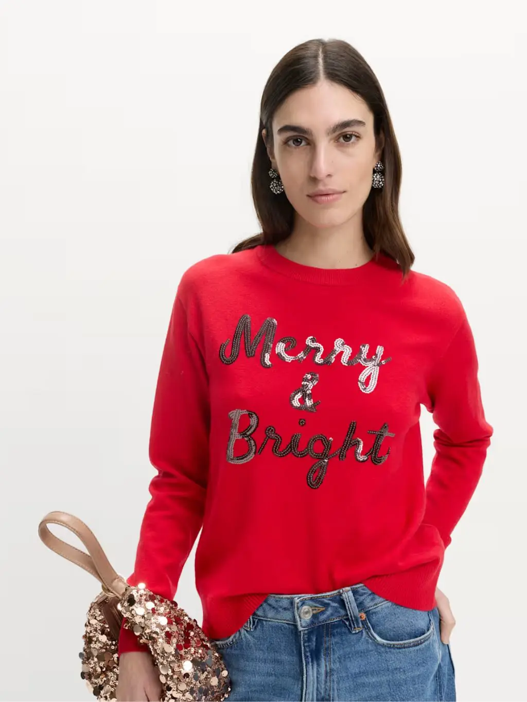 A woman wears a red jumper with the slogan Merry & Bright on it 