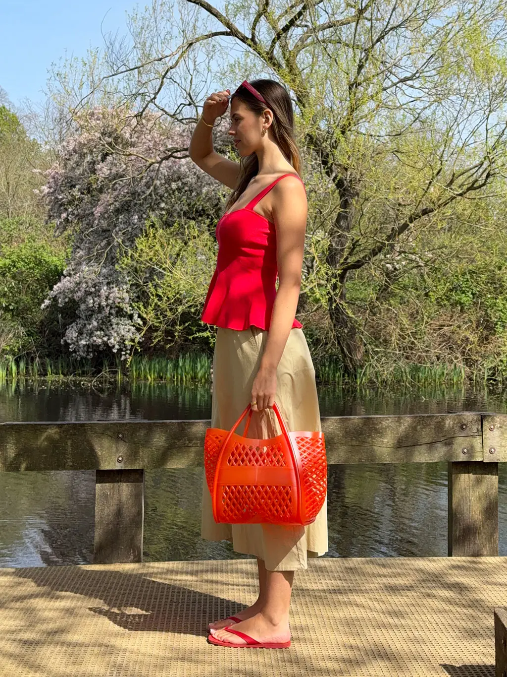 Woman in red peplum top, linen trousers, and jelly bag